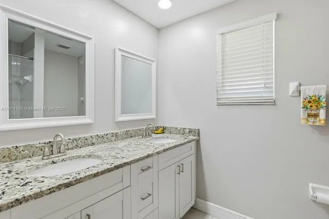 a bathroom with a granite countertop sink and a mirror