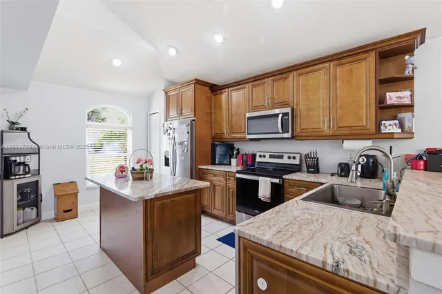 a kitchen with stainless steel appliances granite countertop a stove top oven a sink dishwasher and wooden cabinets with wooden floor