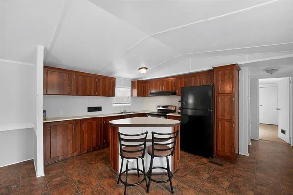 a kitchen with stainless steel appliances a refrigerator a stove a sink and chairs