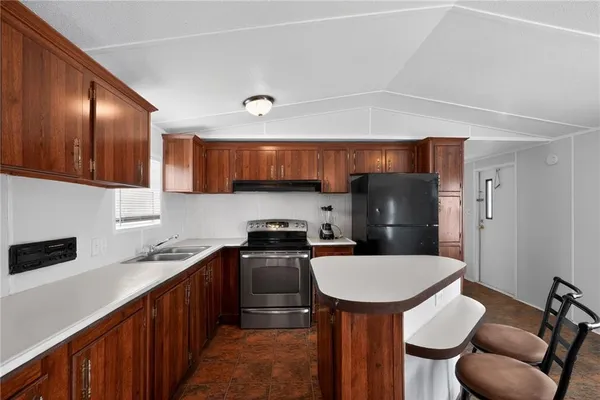 a kitchen with stainless steel appliances a sink a stove a refrigerator cabinets and a dining table