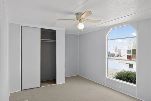 an empty room with wooden floor fan and windows