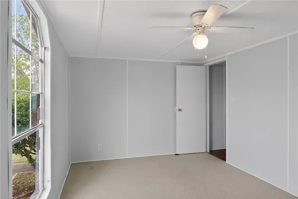 an empty room with windows and ceiling fan