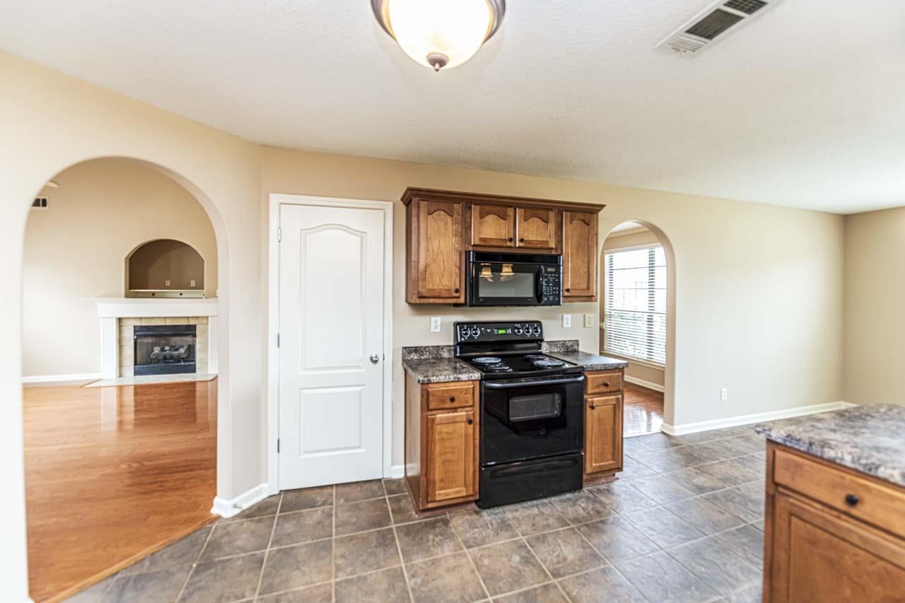 260 Terry Road Oakland, TN 38068 - Photo 11 of 33 Kitchen featuring a tile fireplace, dark hardwood / wood-style floors, and black appliances