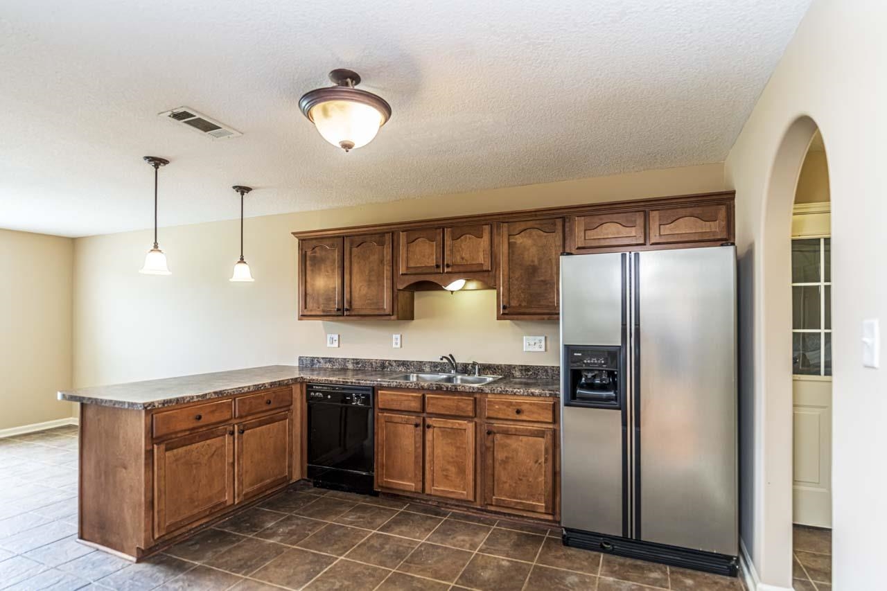 260 Terry Road Oakland, TN 38068 - Photo 14 of 33 Kitchen featuring dark tile patterned floors, kitchen peninsula, black dishwasher, decorative light fixtures, and stainless steel refrigerator with ice dispenser