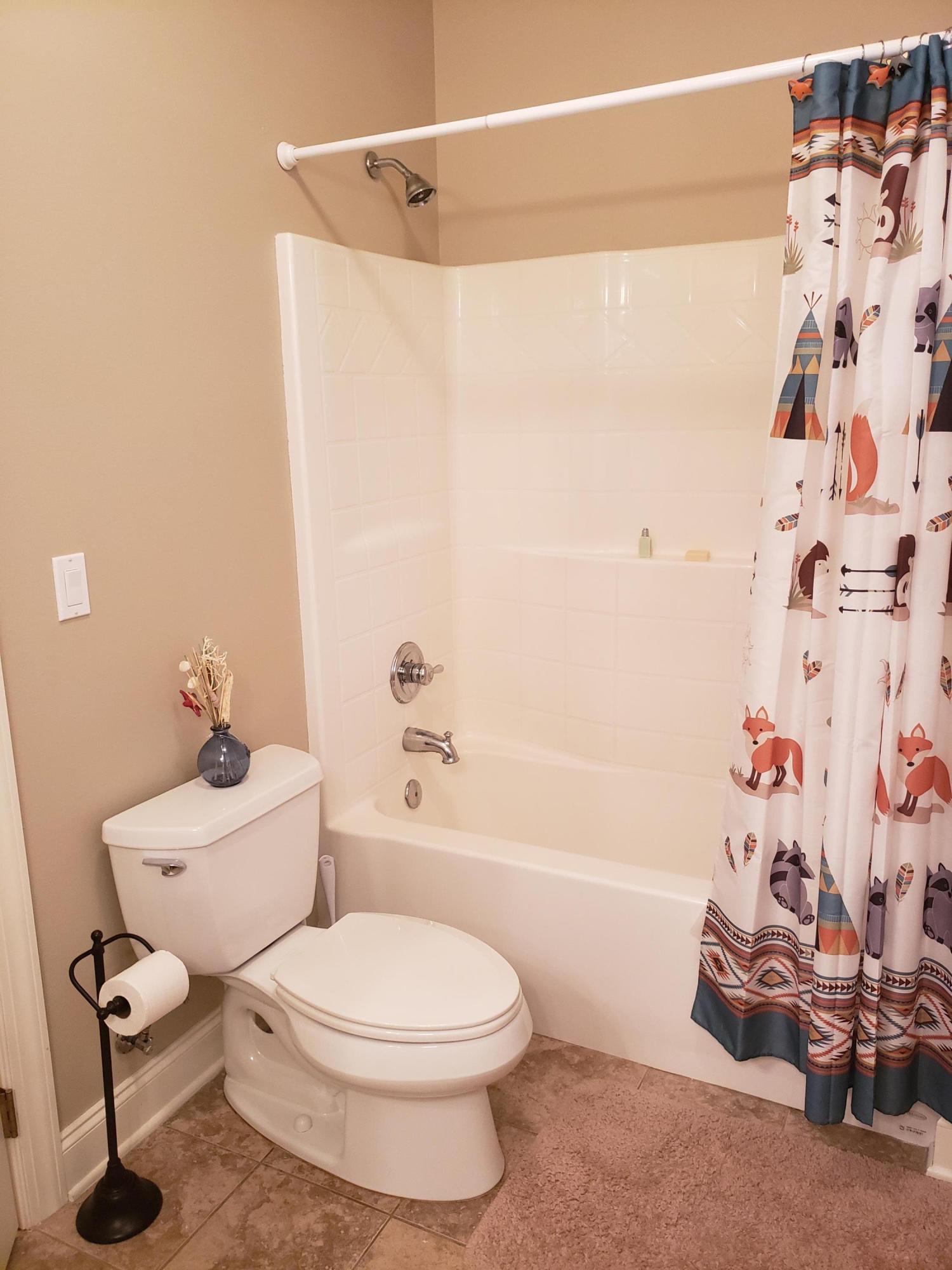 456 Windchime Way Freeport, FL 32439 - Photo 16 of 29 a white toilet sitting next to a bath tub and a shower curtain