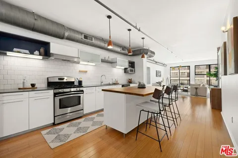 a kitchen with stainless steel appliances granite countertop a stove a sink dishwasher and a refrigerator with wooden floor