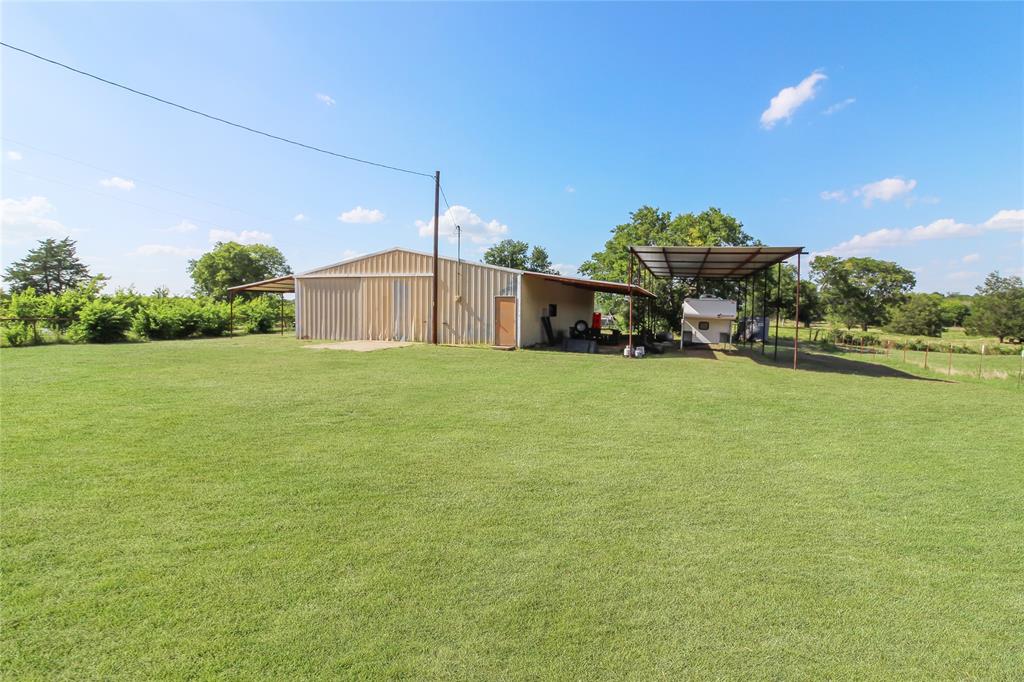 1001 Sandy Ridge Road Scurry, TX 75158 - Photo 6 of 35 Expansive green lawn with a large utility building featuring metal siding and an attached covered carport structure