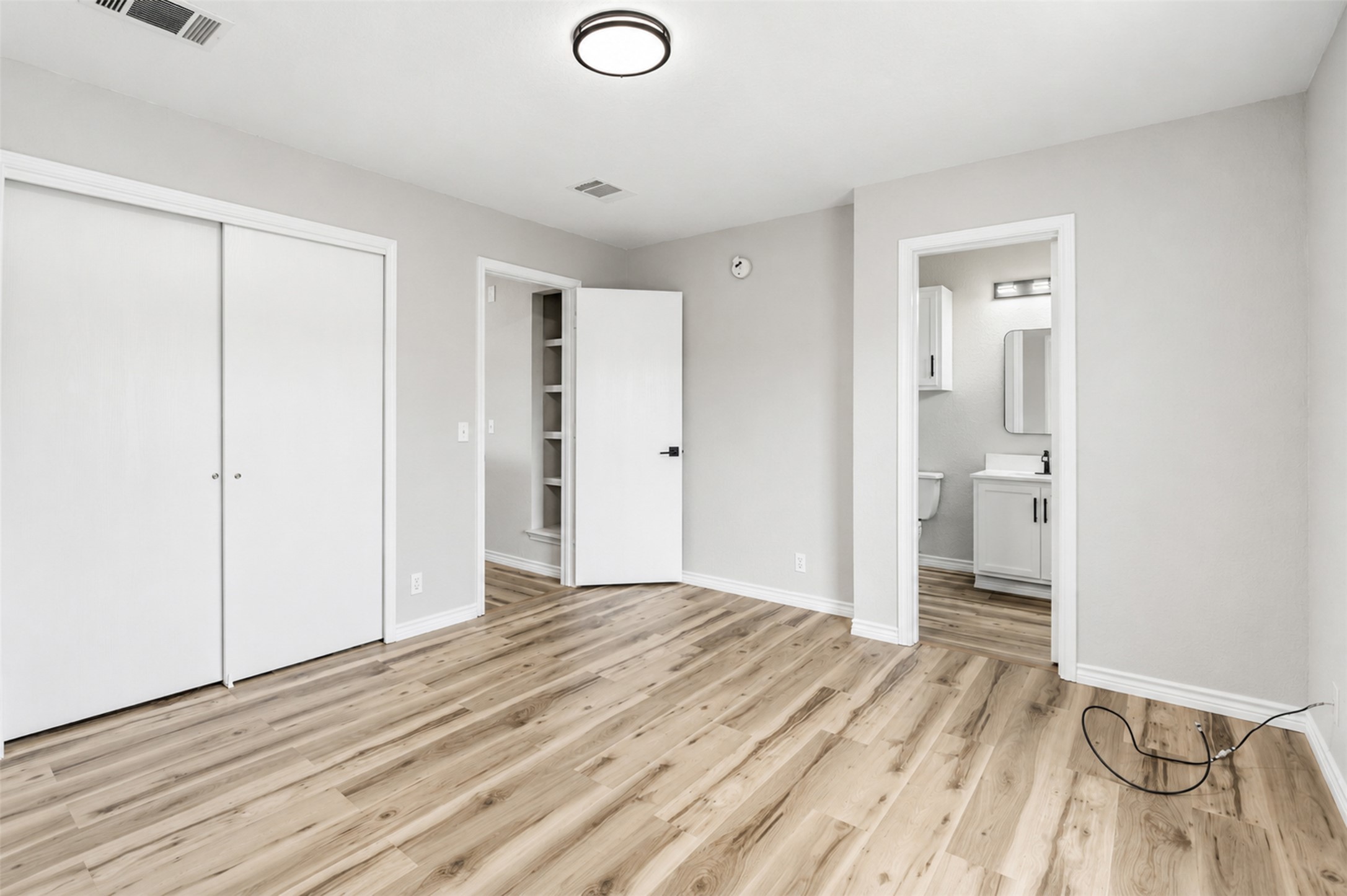 4523 Secure Lane Austin, TX 78725 - Photo 25 of 40 Laminate flooring extends into a spacious bedroom with a private bathroom access.