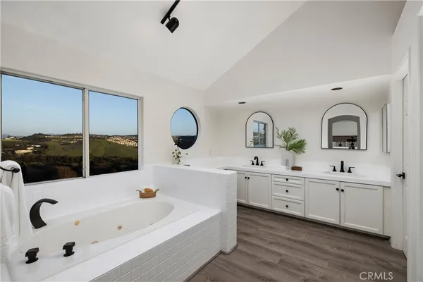 a bathroom with a tub a sink and a large mirror