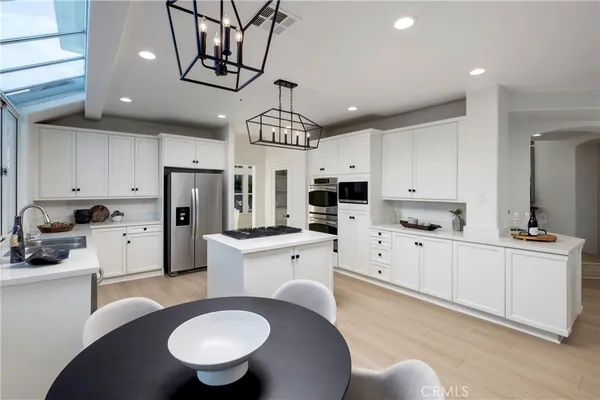 a kitchen with stainless steel appliances granite countertop a sink a stove a refrigerator cabinets and chairs