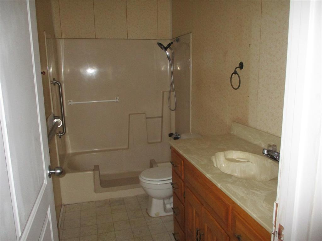 310 County Road 1495 Emory, TX 75440 - Photo 19 of 24 a bathroom with a granite countertop sink a toilet and shower