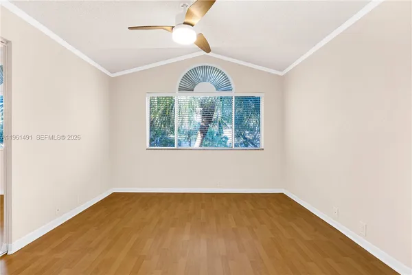 an empty room with chandelier fan and windows