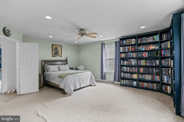a spacious bedroom with a bed and a book shelf