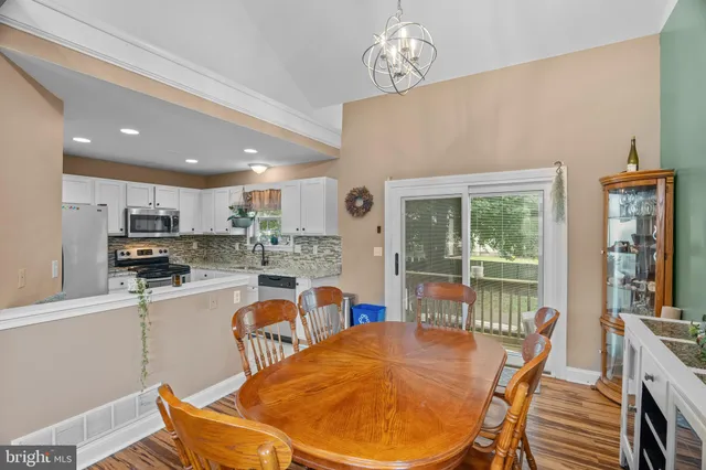 a dining room with stainless steel appliances furniture a large window and a kitchen view
