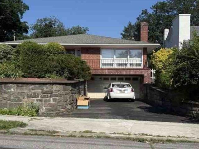 View of front of property with an attached garage, driveway, and a chimney