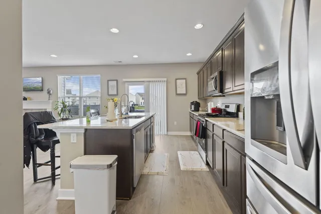 a kitchen with stainless steel appliances kitchen island granite countertop a sink refrigerator and cabinets