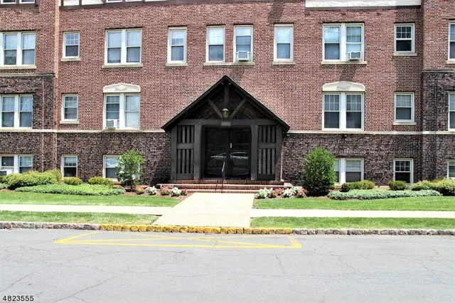 a front view of a house with a garden and trees