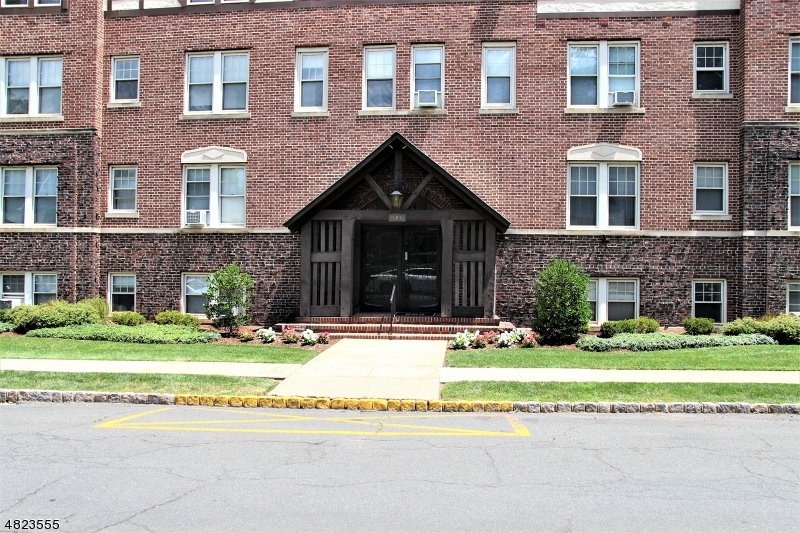 a front view of a house with a garden and trees