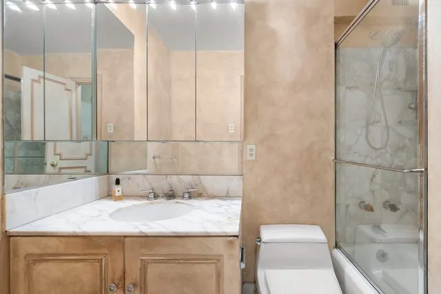 a bathroom with a granite countertop sink a toilet and shower