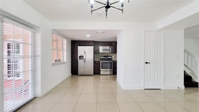 a view of a kitchen with refrigerator and wooden floor