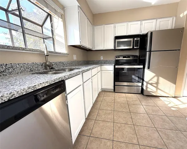 a kitchen with stainless steel appliances granite countertop a sink stove and microwave