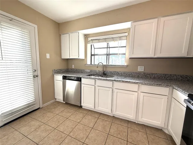 a kitchen with granite countertop white cabinets stainless steel appliances a sink and a window
