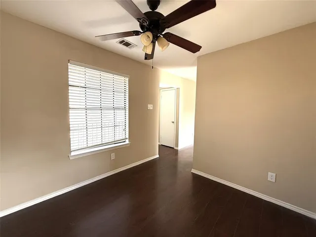an empty room with wooden floor fan and windows
