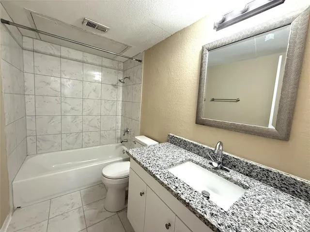 a bathroom with a granite countertop sink a toilet and shower