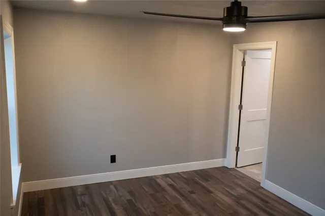 an empty room with wooden floor and chandelier fan