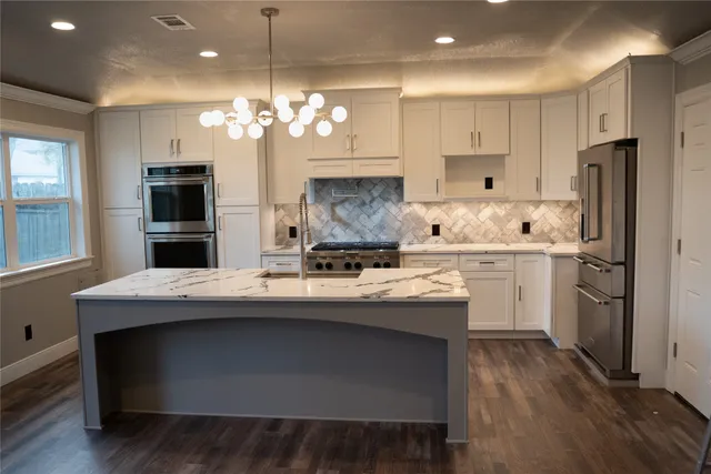 a kitchen with kitchen island granite countertop a sink refrigerator and cabinets