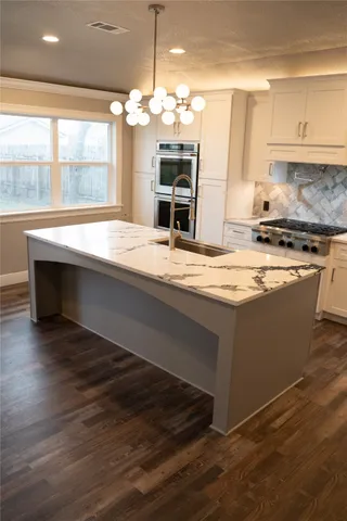 a kitchen with kitchen island granite countertop a sink and a stove