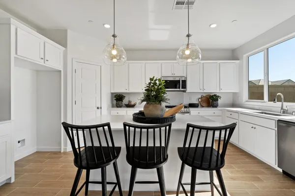 a kitchen with a dining table chairs and white cabinets