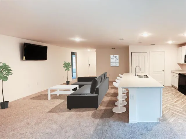 a living room with furniture a flat screen tv and kitchen view