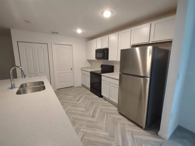 a kitchen with a refrigerator sink and cabinets