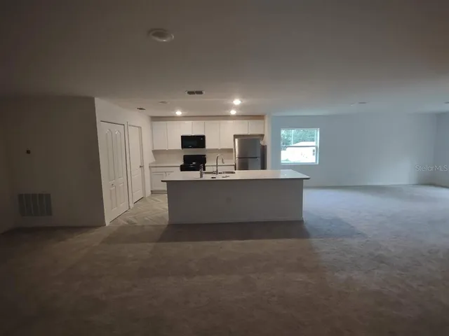 a view of living room with stainless steel appliances wooden cabinets