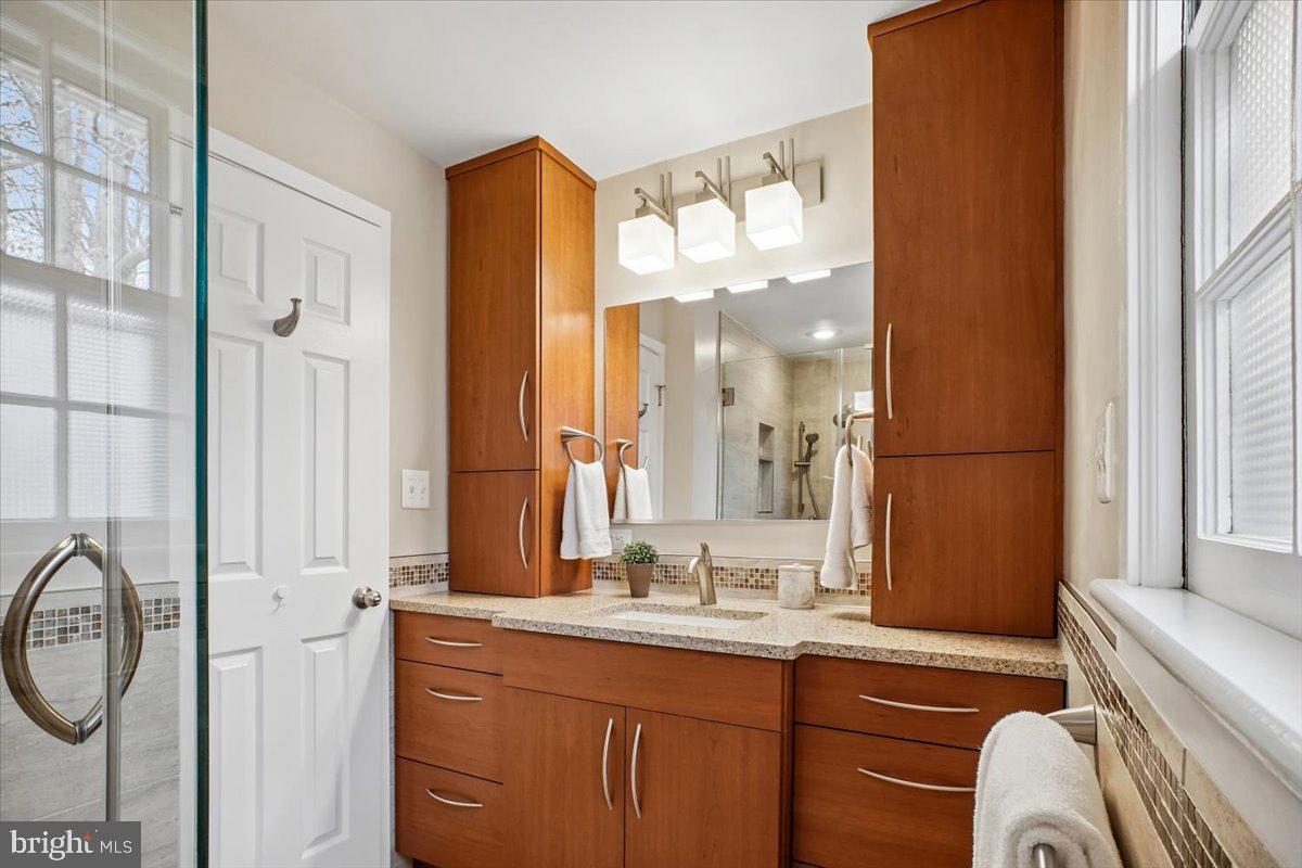 10113 Cardinal Road Fairfax, VA 22030 - Photo 30 of 59 a bathroom with a sink a mirror a vanity and a shower