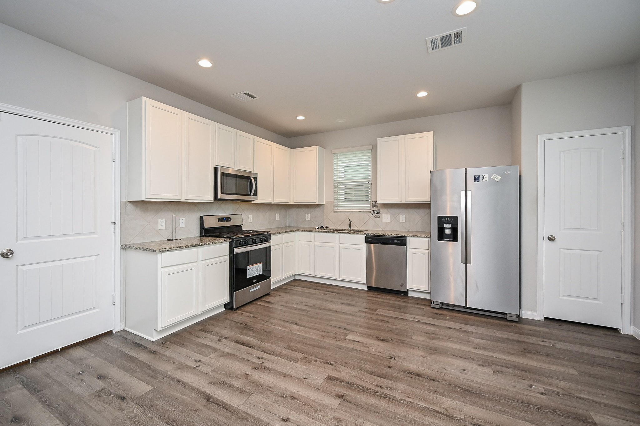 22002 Imperious Parkway Houston, TX 77073 - Photo 6 of 20 a kitchen with granite countertop a refrigerator oven a sink dishwasher and white cabinets with wooden floor