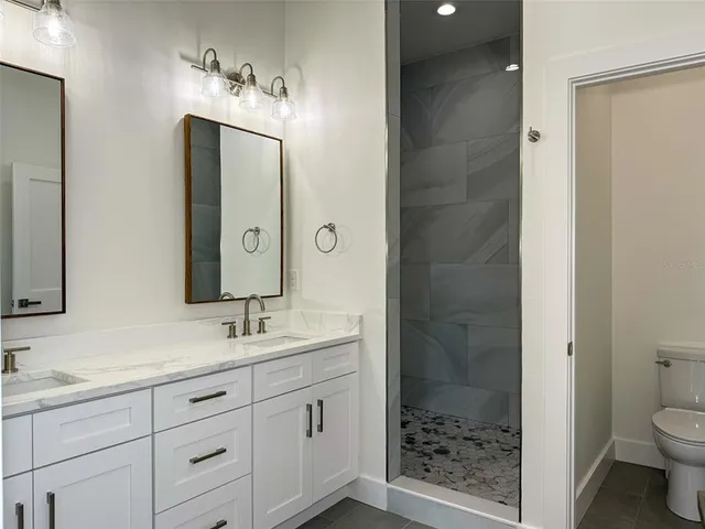 a bathroom with a granite countertop toilet a sink and shower