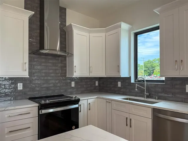 a kitchen with stainless steel appliances granite countertop white cabinets sink and window
