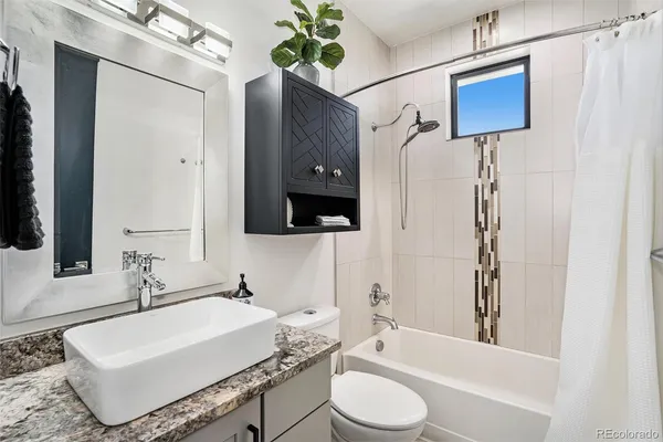 a bathroom with a granite countertop sink a toilet a mirror and bathtub