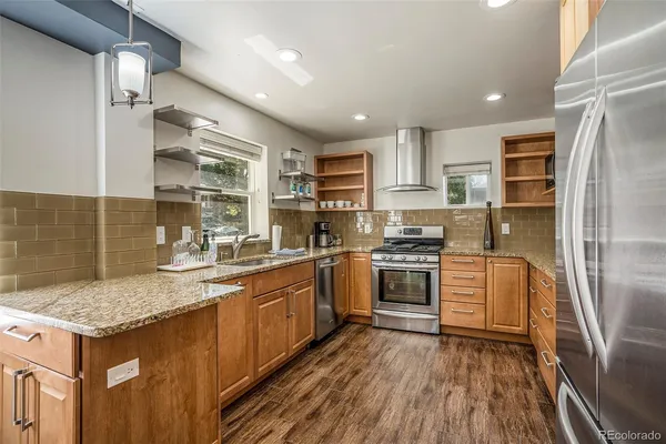 a kitchen with granite countertop kitchen island stainless steel appliances a sink stove and refrigerator