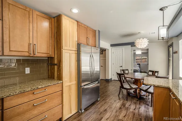 a kitchen with granite countertop stainless steel appliances refrigerator dining table and chairs