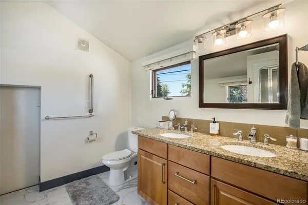 a bathroom with a granite countertop toilet sink and mirror