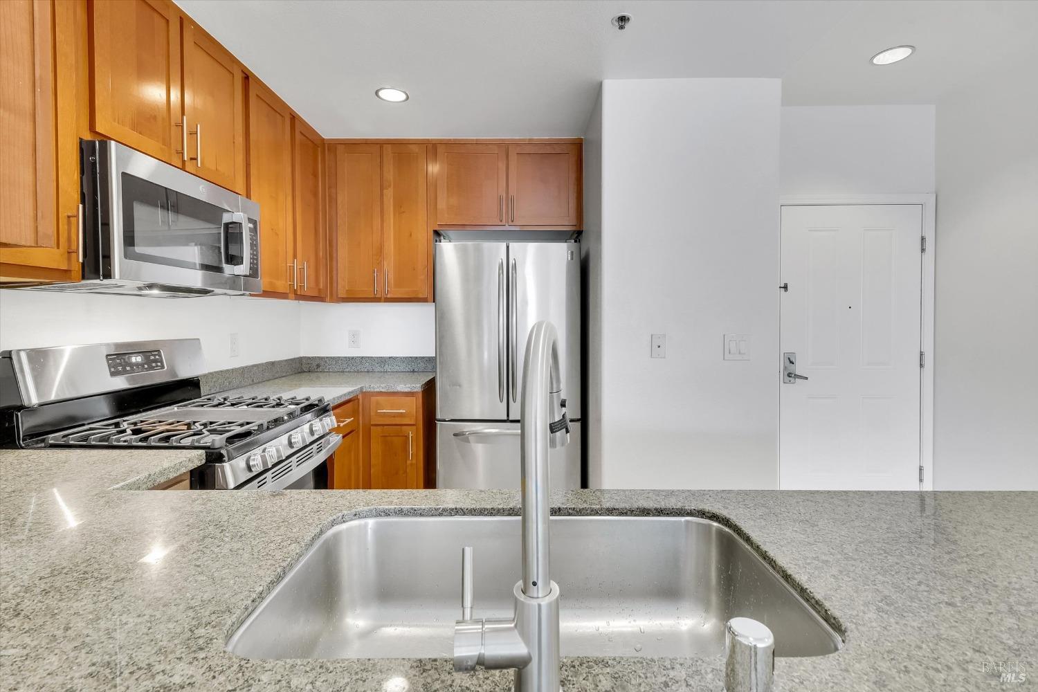 423 7th Street, Unit 105 Oakland, CA 94607 - Photo 12 of 28 a kitchen with stainless steel appliances granite countertop a sink stove and refrigerator