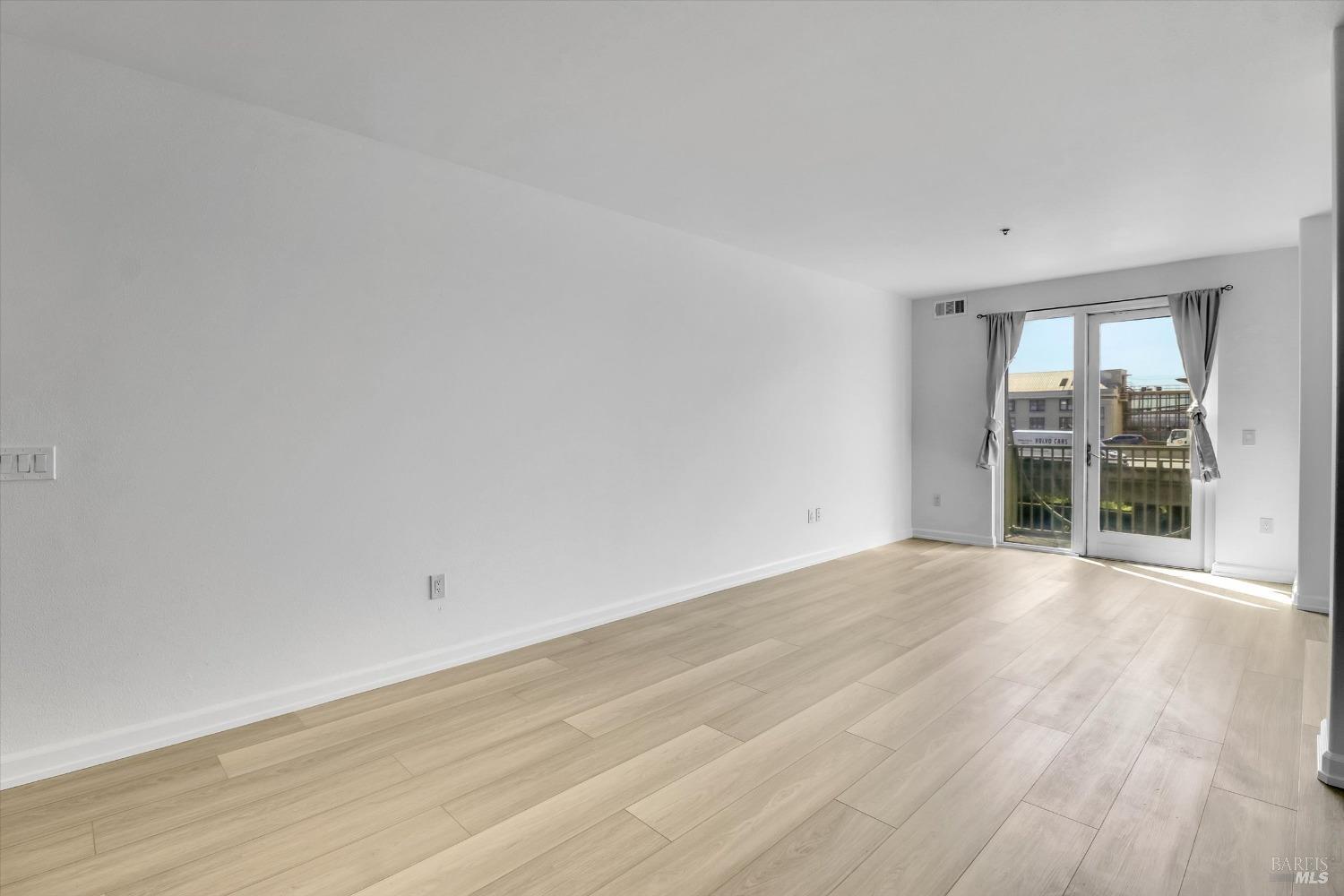 423 7th Street, Unit 105 Oakland, CA 94607 - Photo 13 of 28 an empty room with wooden floor and windows