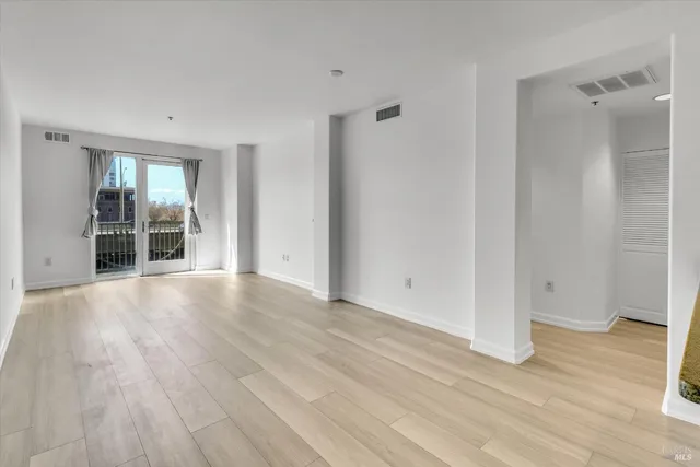 a view of empty room with wooden floor and window