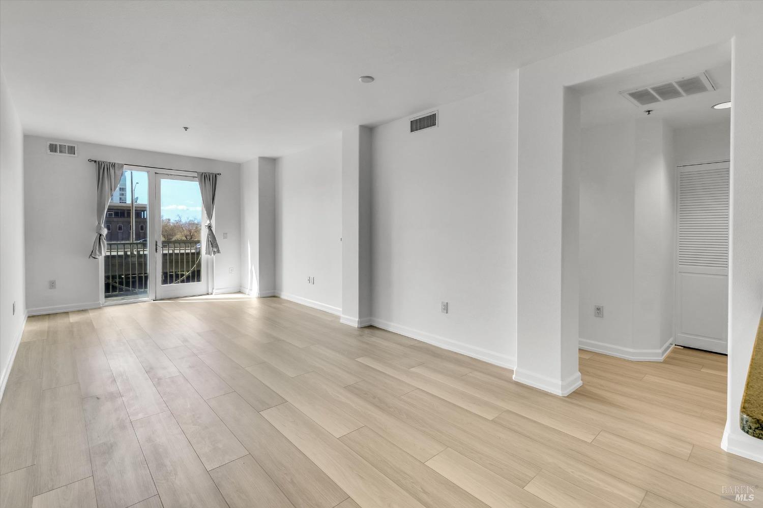 423 7th Street, Unit 105 Oakland, CA 94607 - Photo 14 of 28 a view of an empty room with wooden floor and a window