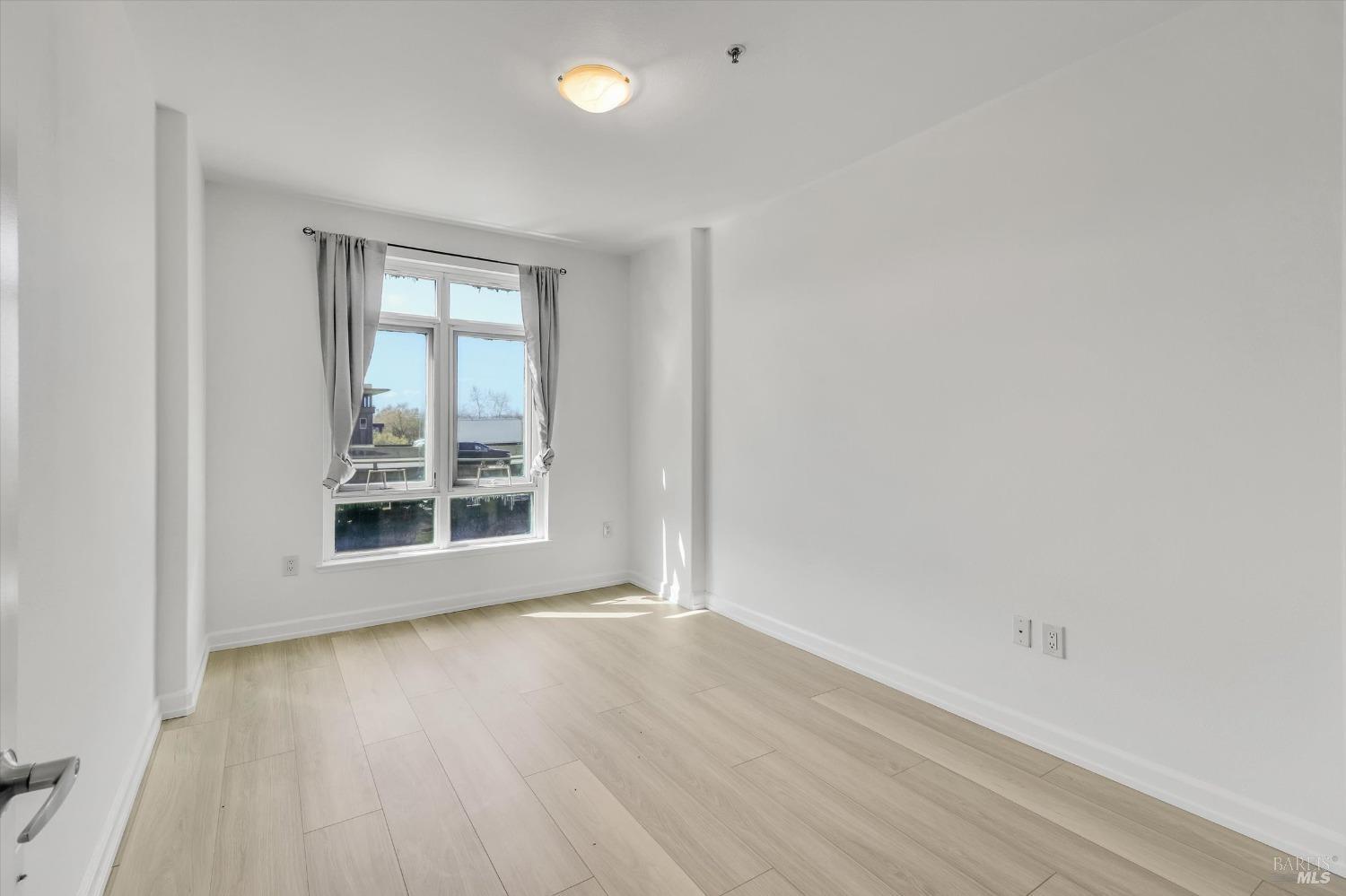 423 7th Street, Unit 105 Oakland, CA 94607 - Photo 18 of 28 an empty room with wooden floor and windows