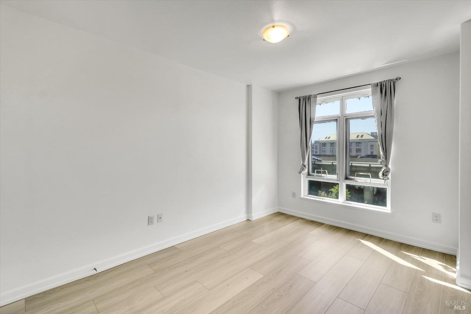 423 7th Street, Unit 105 Oakland, CA 94607 - Photo 19 of 28 an empty room with wooden floor and windows