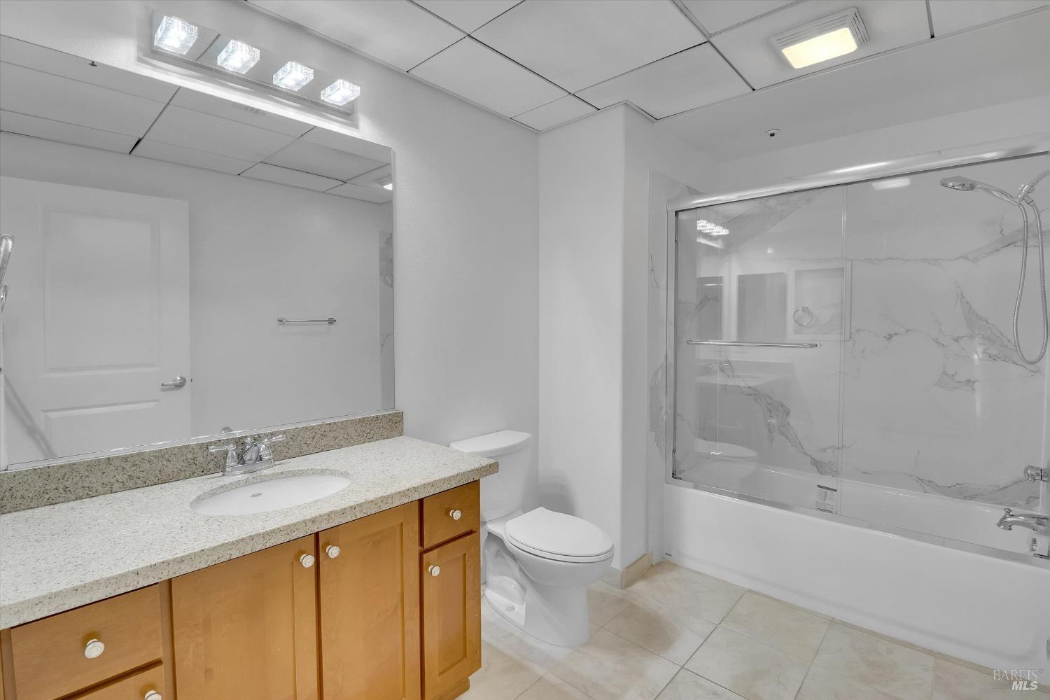 423 7th Street, Unit 105 Oakland, CA 94607 - Photo 23 of 28 a bathroom with a granite countertop sink a toilet and shower